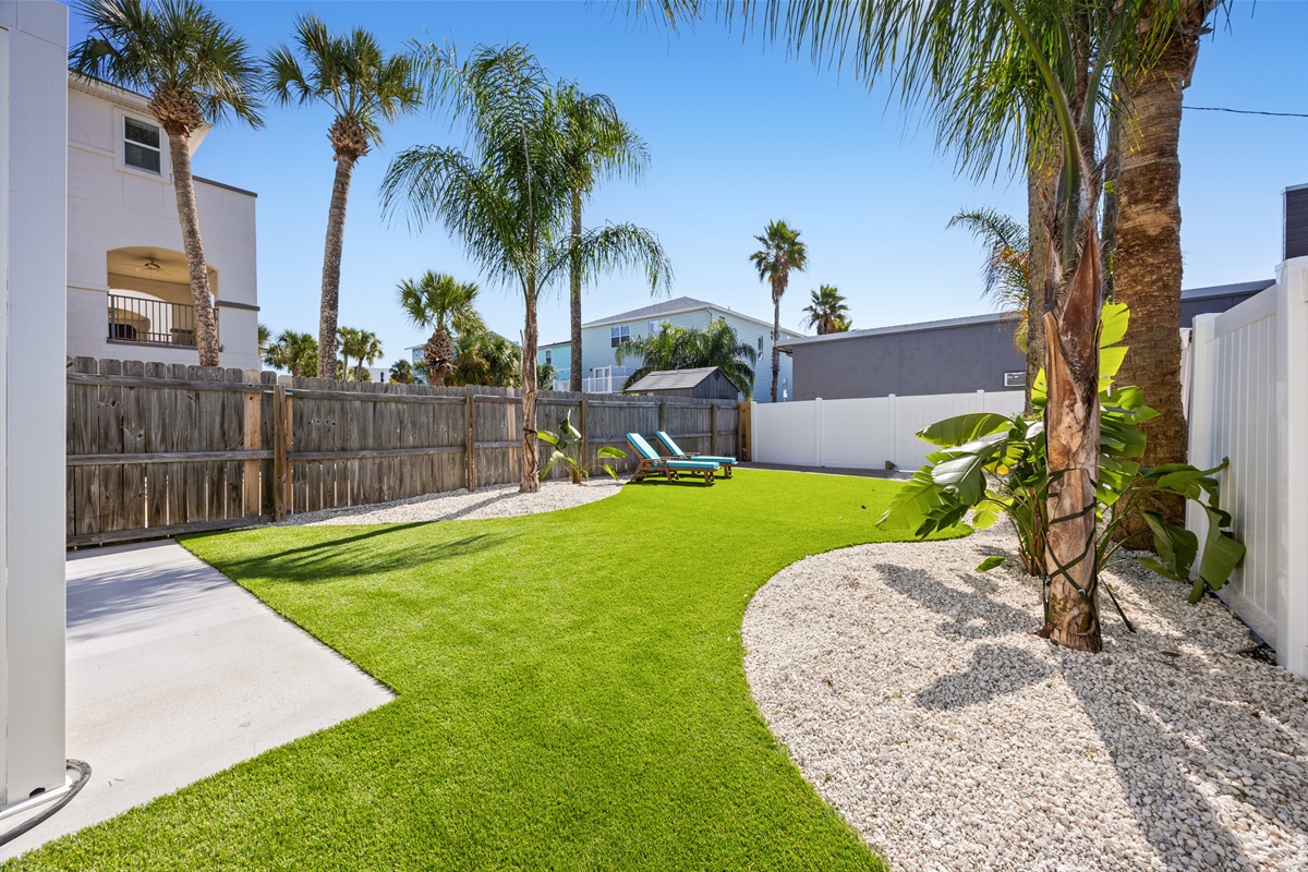Wide backyard view showing lawn and loungers