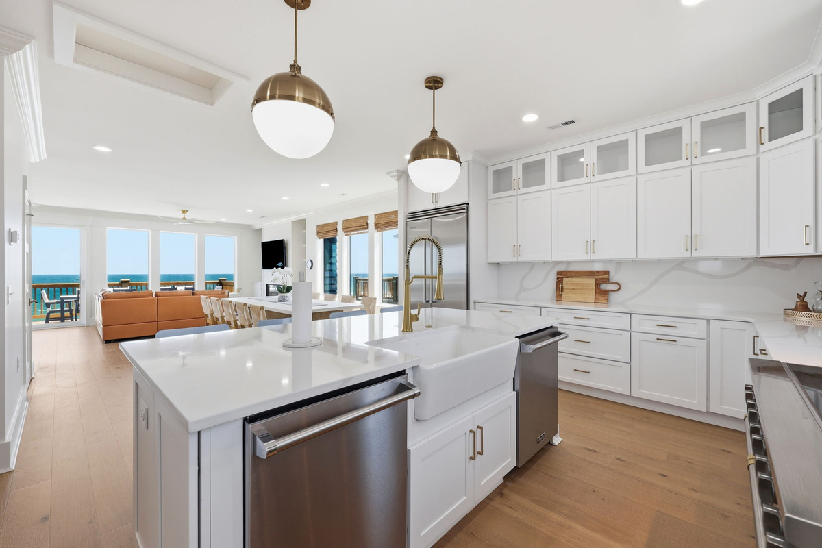 Modern coastal kitchen with large island, bar seating, and open layout connecting to the dining and oceanview living area