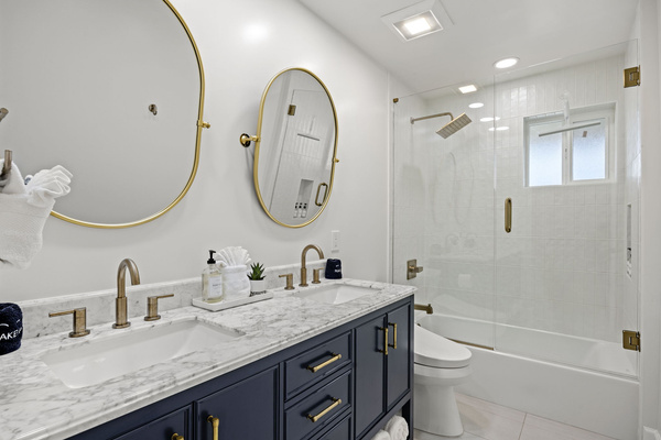 Bright and modern bathroom with dual sinks and a glass-enclosed tub and shower