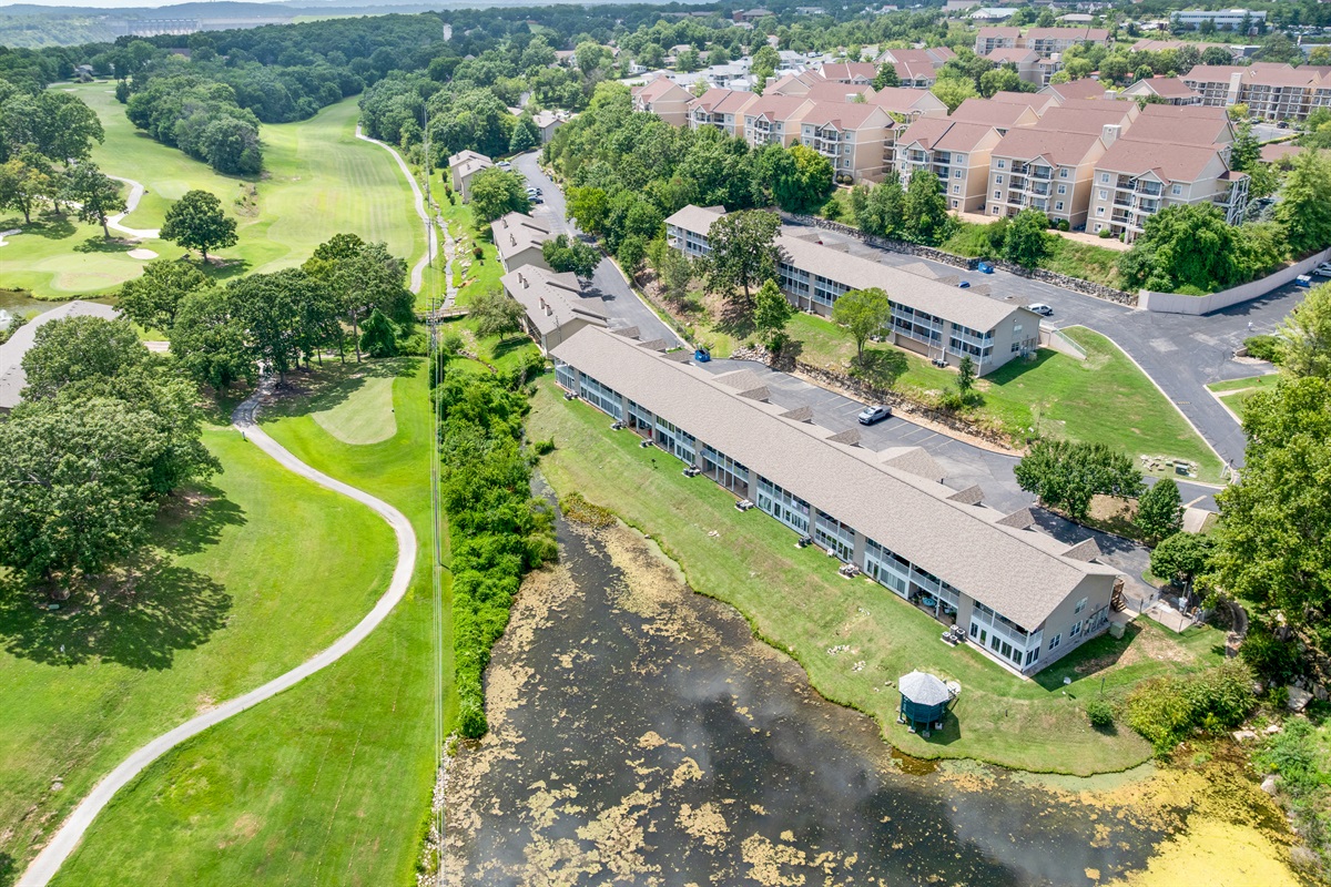 A second aerial angle highlights the condo’s position amid mature trees, water, and a peaceful residential setting.