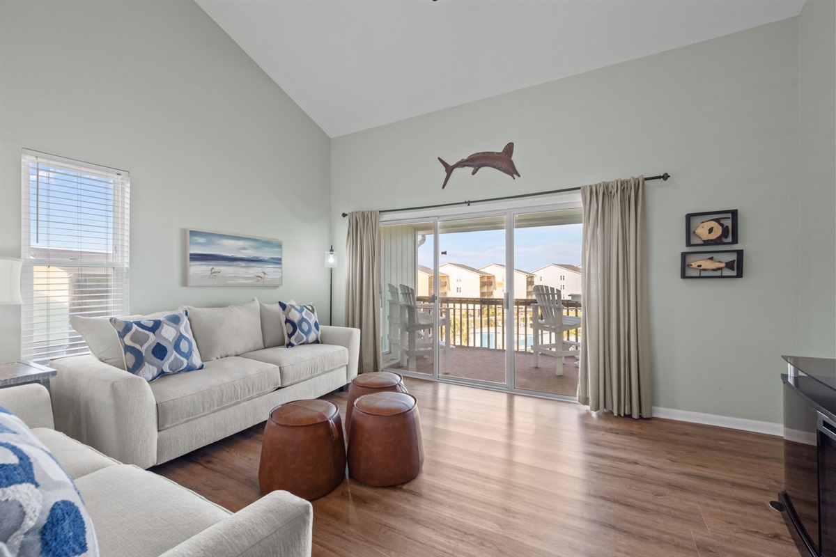 A bright coastal lounge with sliding doors leading to the private balcony