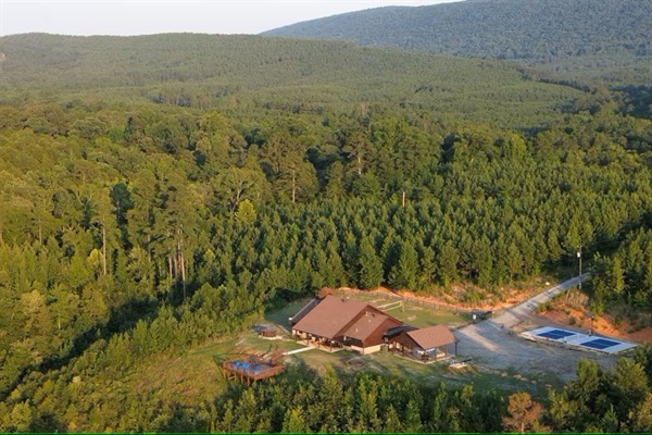 Aerial showing the cabin nestled among forested hills and private acreage.
