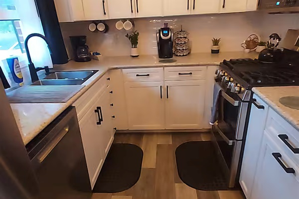 This kitchen features a sparkly peppercorn countertop & generous prep space. It includes two hidden trash cans, a bottle jet dishwasher, XL microwave & a double oven with air fryer & convection baking. The backyard window view is simply dreamy.