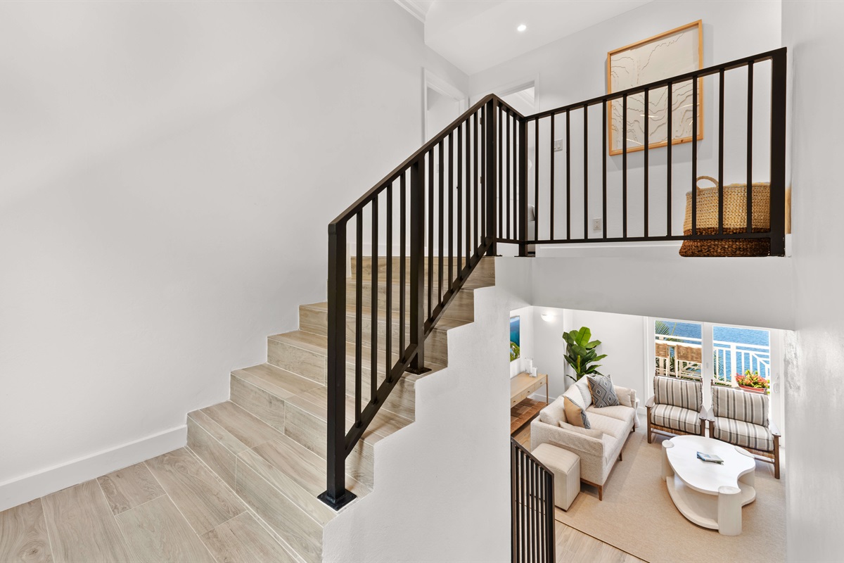 Open stairwell with natural light and modern railing design connecting both floors.