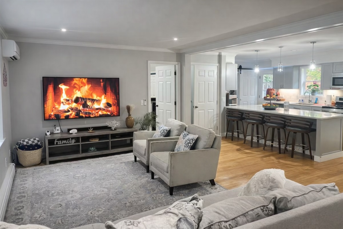 Open-plan main level living area with large TV and fireplace