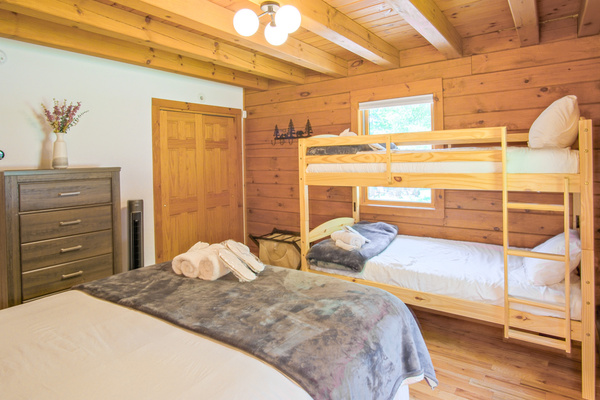 Offering a full size bed and a set of twin bunk beds, this second guest bedroom is perfect for a family, blending coziness and luxurious feel
