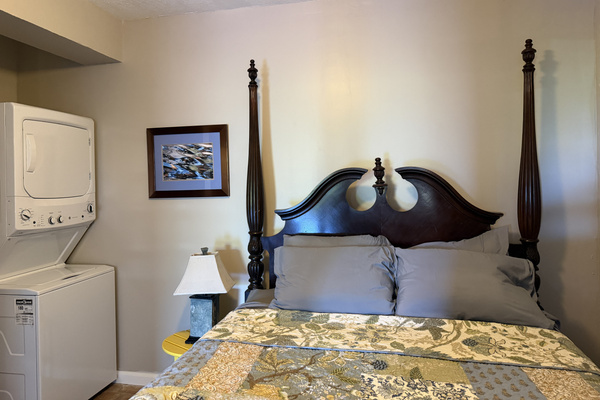 This comfortable apartment bedroom combines traditional style with tropical charm. The highlight is an elegant carved four-poster bed. Guests will also enjoy the ultimate convenience of having a stacked washer and dryer right inside the room.