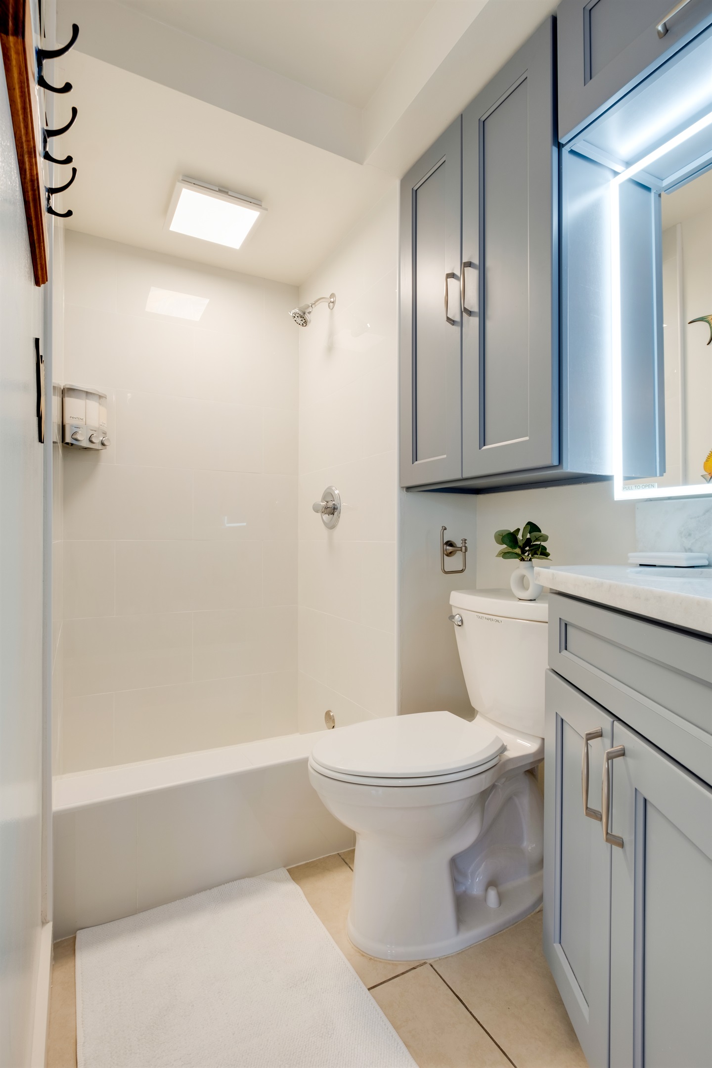 Refresh and rejuvenate in this bright, modern bathroom featuring sleek tile finishes and spa-inspired design. A perfect place to unwind after a day of Waikīkī sun and surf, offering both comfort and contemporary island style.