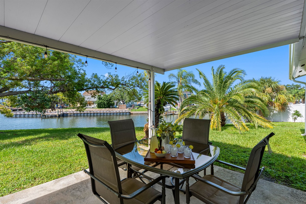Enjoy tranquil mornings and breezy afternoons on this covered patio that overlooks a peaceful canal and lush palm trees.