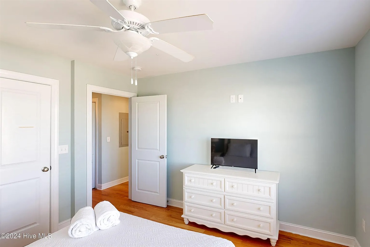 Guest bedroom equipped with a flat-screen TV and ceiling fan for comfort