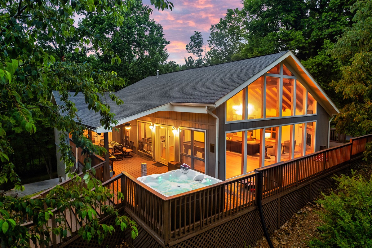Your private Smoky Mountain escape; cozy lights glowing from a chalet nestled among the trees with a wraparound deck to unwind.