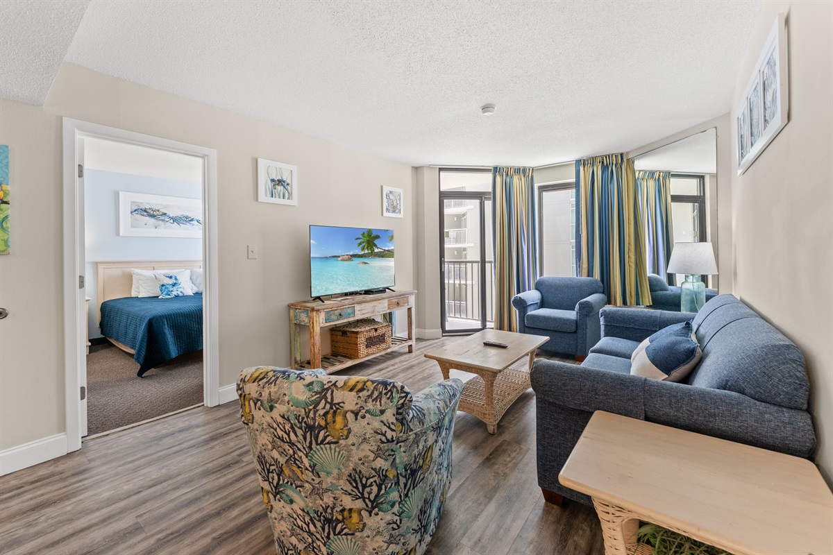 Large living room area with sleeper sofa, access to the balcony and large screen TV