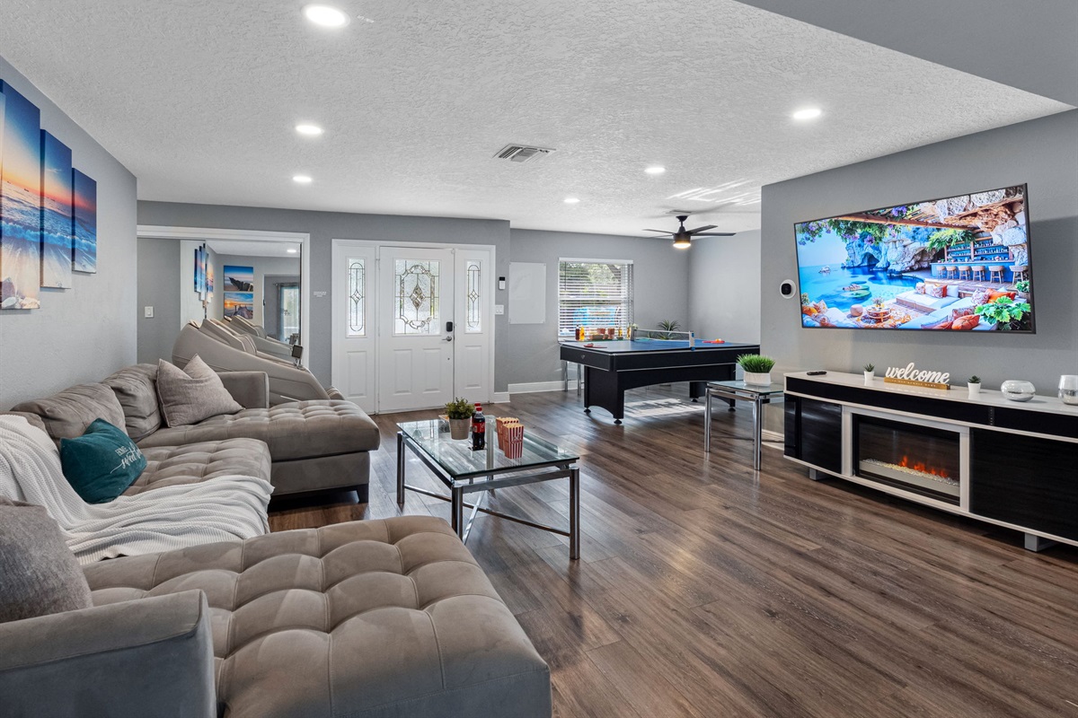 A large wall-mounted TV, cozy seating, and movie-time snacks on the coffee table make this space ideal for a home theater experience.