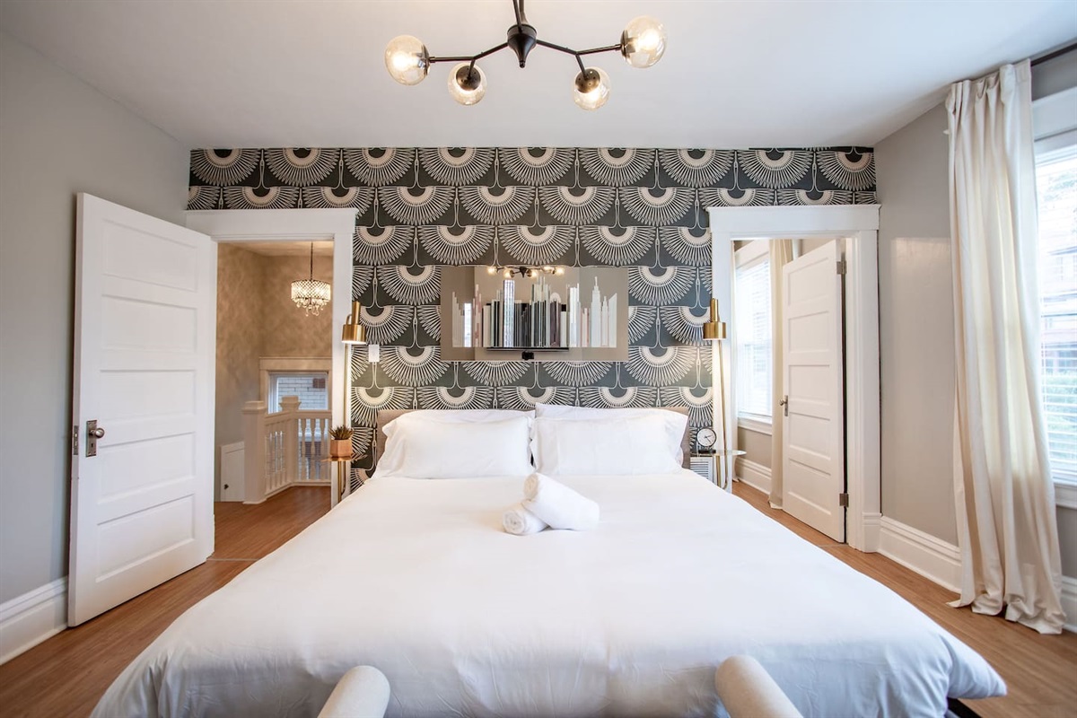 Charming queen bedroom featuring beautiful wallpaper, adding a touch of personality and style to the space for a cozy and inviting atmosphere.