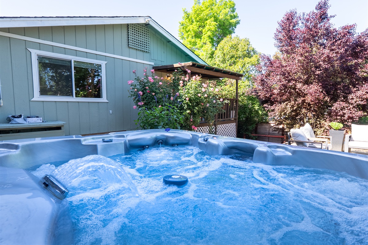 Unwind in the bubbling hot tub surrounded by lush garden views.