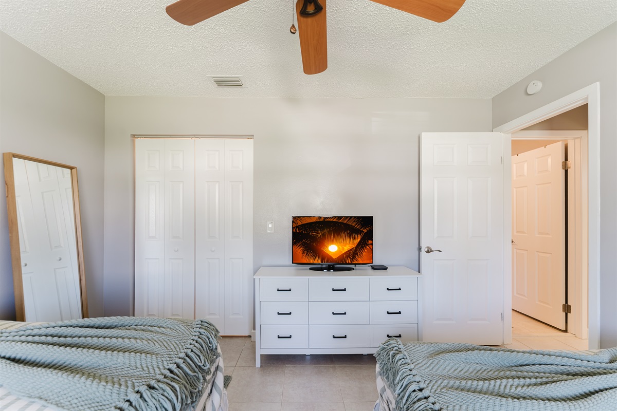 Bright guest bedroom with two queen beds, Smart TV with cable, and ample closet and dresser storage
