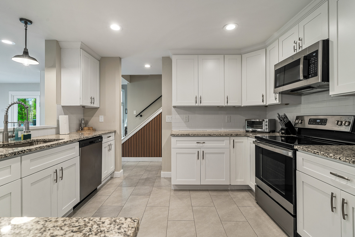 Fully equipped kitchen with white shaker cabinets, granite counters and stainless steel appliances