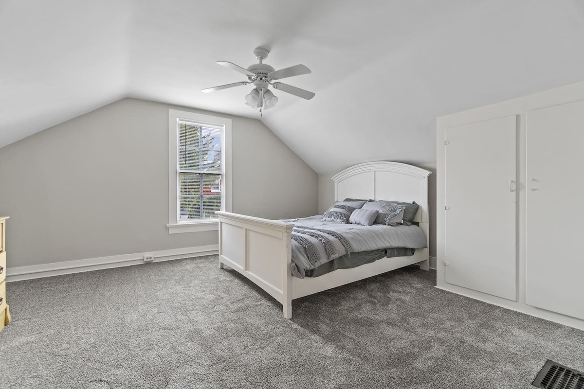 Cozy bedroom featuring a queen-sized bed, a large window with a scenic view, and a beautiful ceiling fan that adds a touch of elegance and comfort to the space.