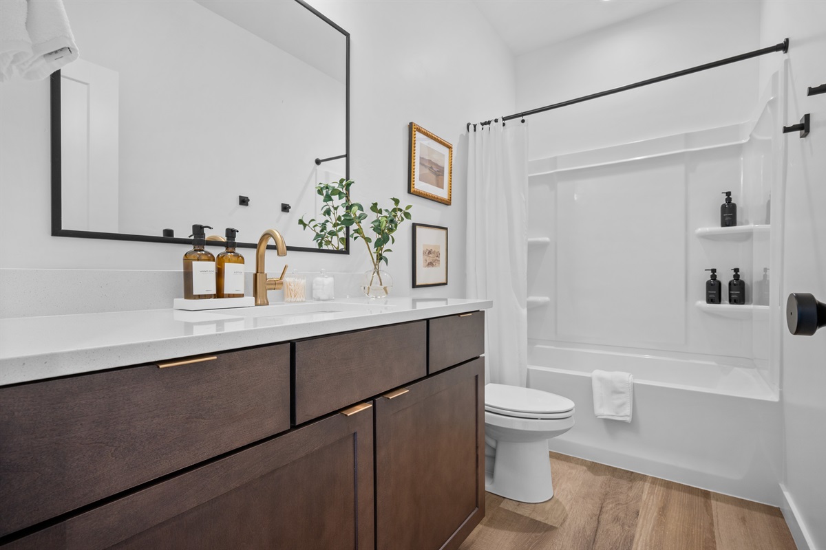 Bright and stylish bathroom featuring a large mirror, quartz counter, and elegant finishes.