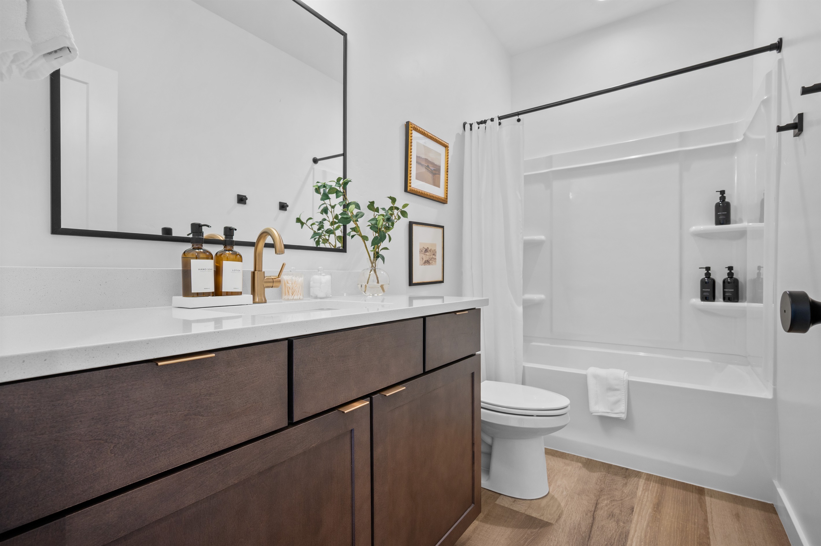Bright and stylish bathroom featuring a large mirror, quartz counter, and elegant finishes.