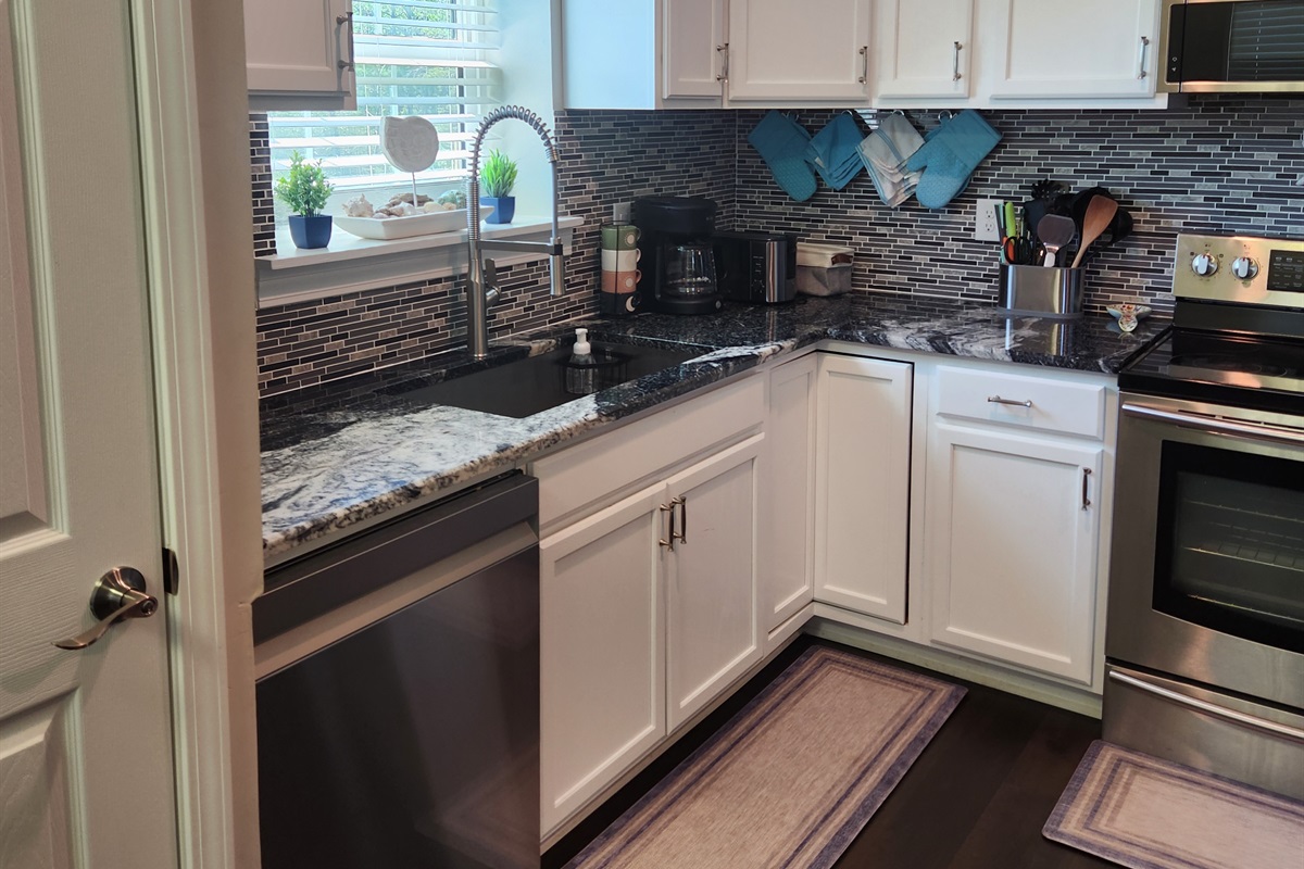 Enjoy cooking in this stylish and functional kitchen featuring crisp white cabinetry, stainless steel appliances, and a modern tile backsplash