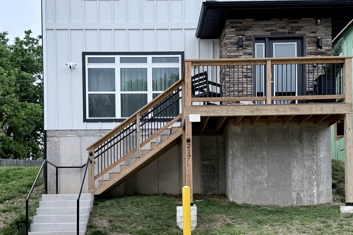 Front elevation of new vacation home with stone exterior at front door. Steps can be avoided by parking in rear parking space. Spacious with nine foot ceilings.