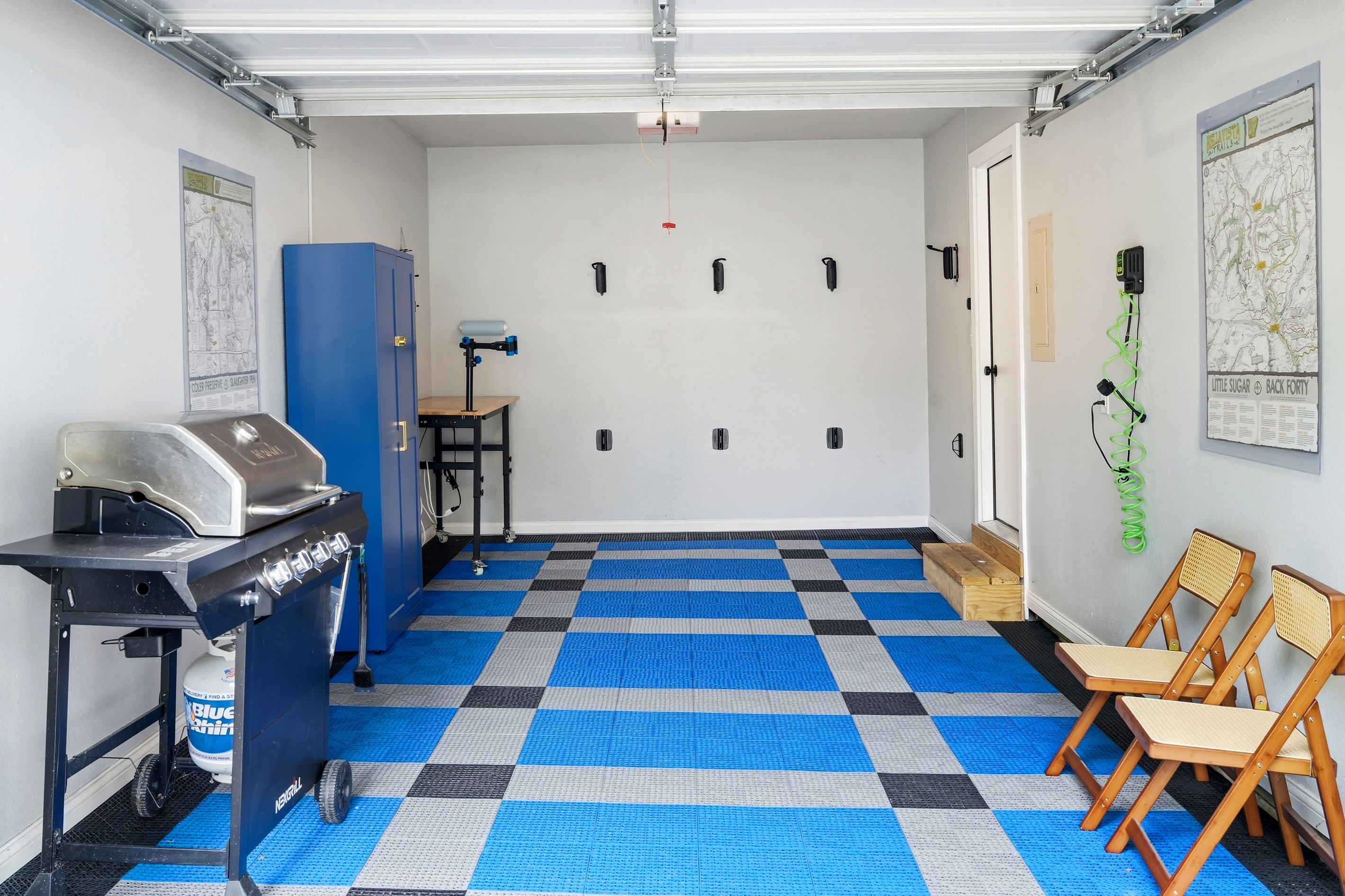 Garage with bike hanging, tire pump, grill and trail maps.