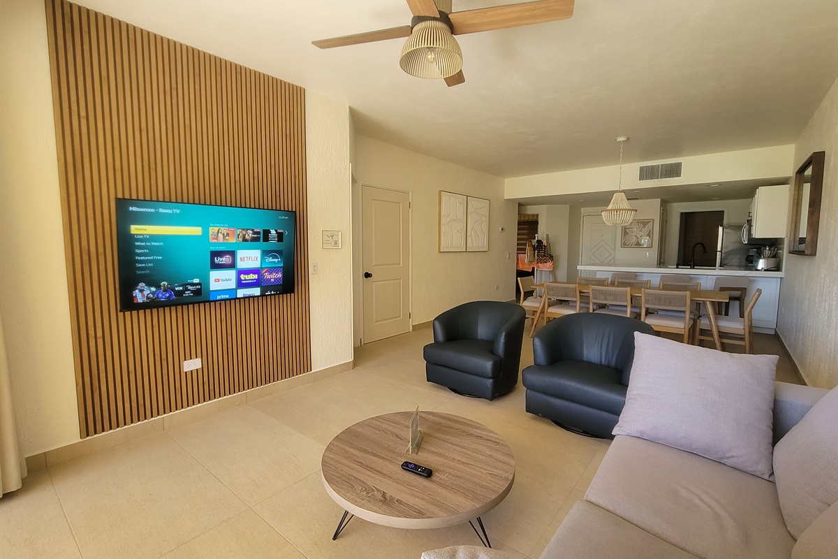 Living room with queen pull out sofa, Roku TV, 2 swivel leather barrel chairs. The newly remodeled media wall adds a modern touch.