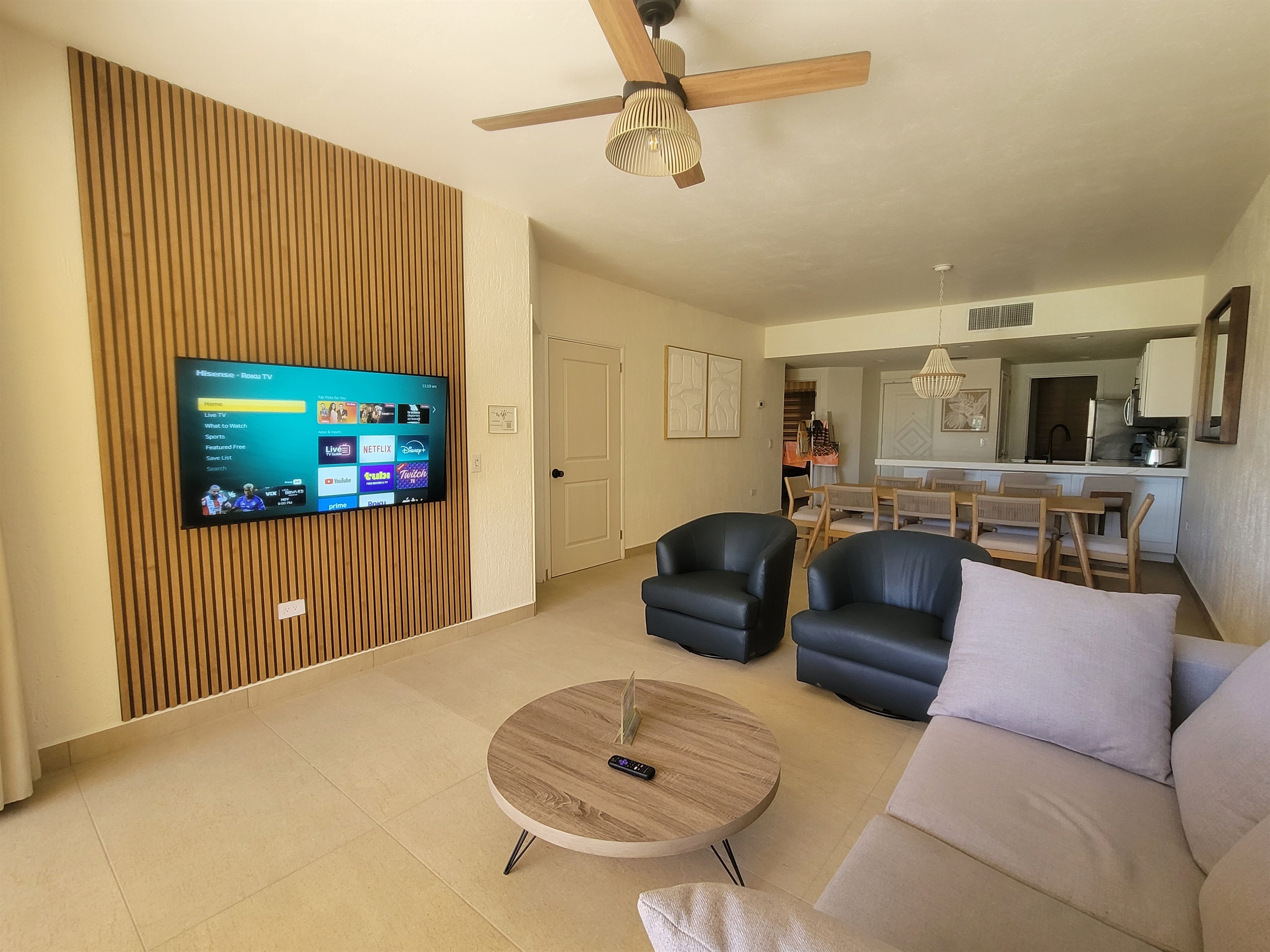Living room with queen pull out sofa, Roku TV, 2 swivel leather barrel chairs. The newly remodeled media wall adds a modern touch.