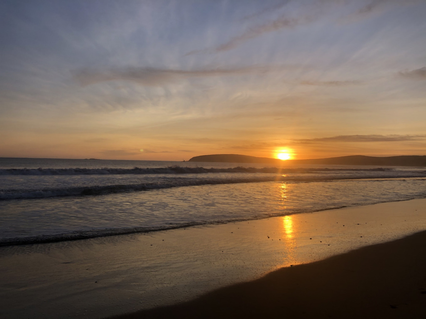 The setting sun reflecting on wet sand