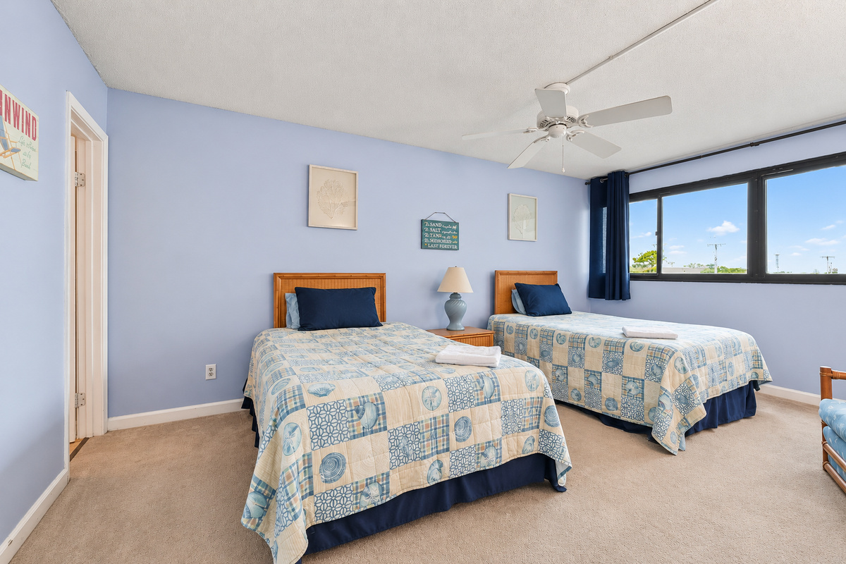 Second Bedroom with two full beds, ceiling fan, wide window view, and ensuite bathroom access.