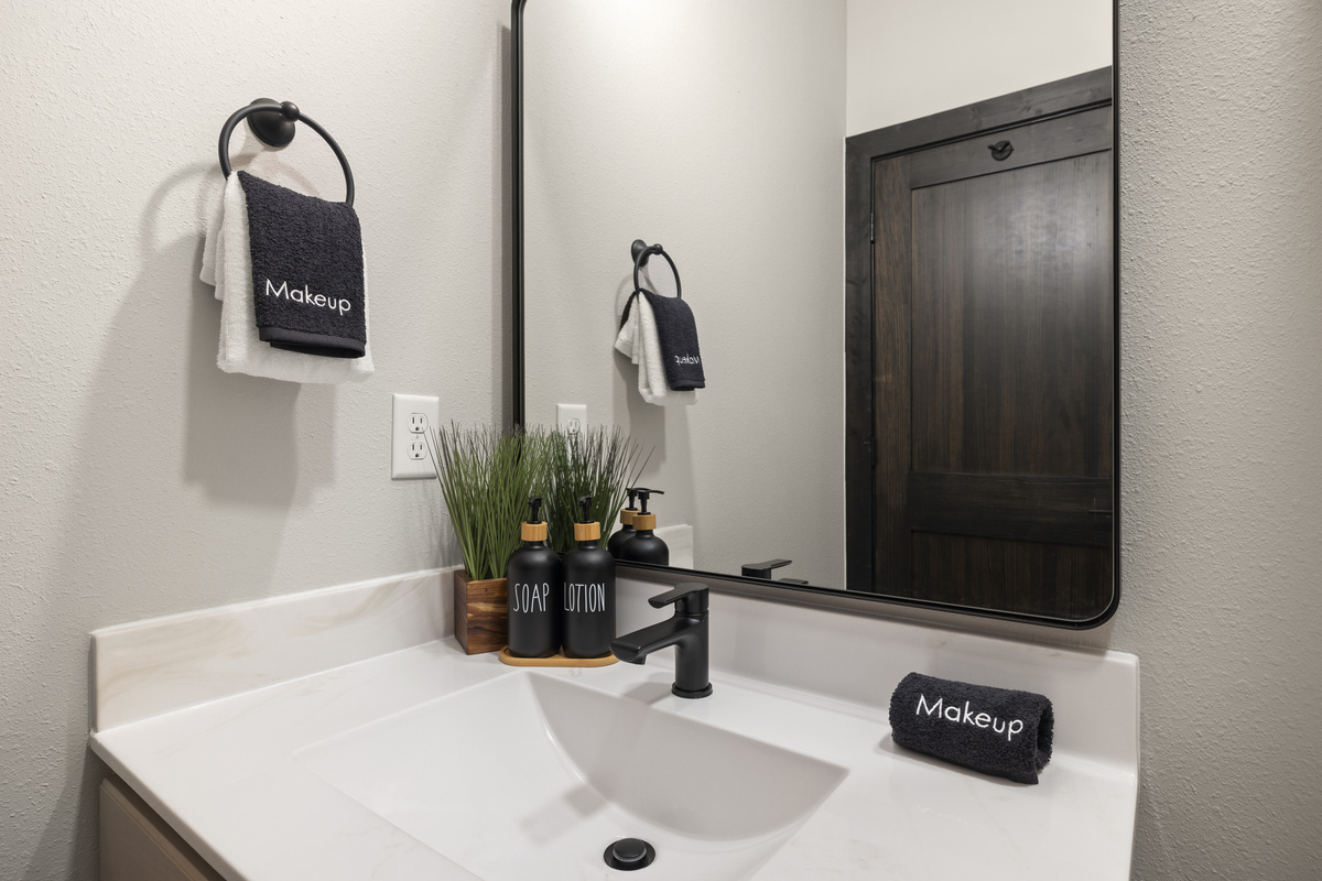 A lit mirror and black-fixture vanity just off the bedroom.