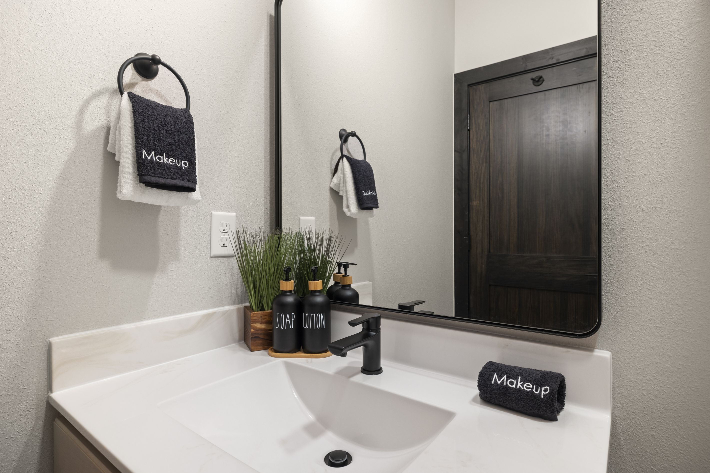 A lit mirror and black-fixture vanity just off the bedroom.
