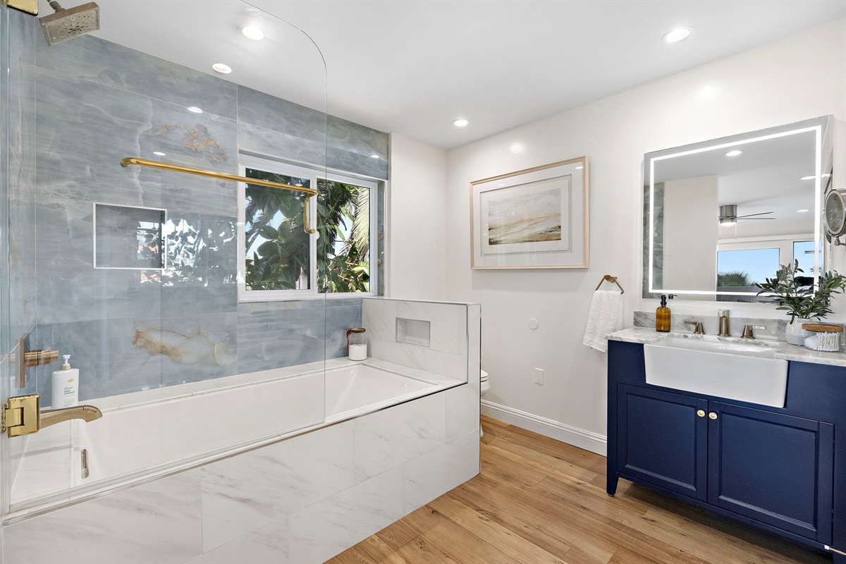 Spa-style en-suite primary bathroom featuring a soaking tub, glass-enclosed shower, custom blue vanity, and refined finishes—complete with Epsom salts for a relaxing soak