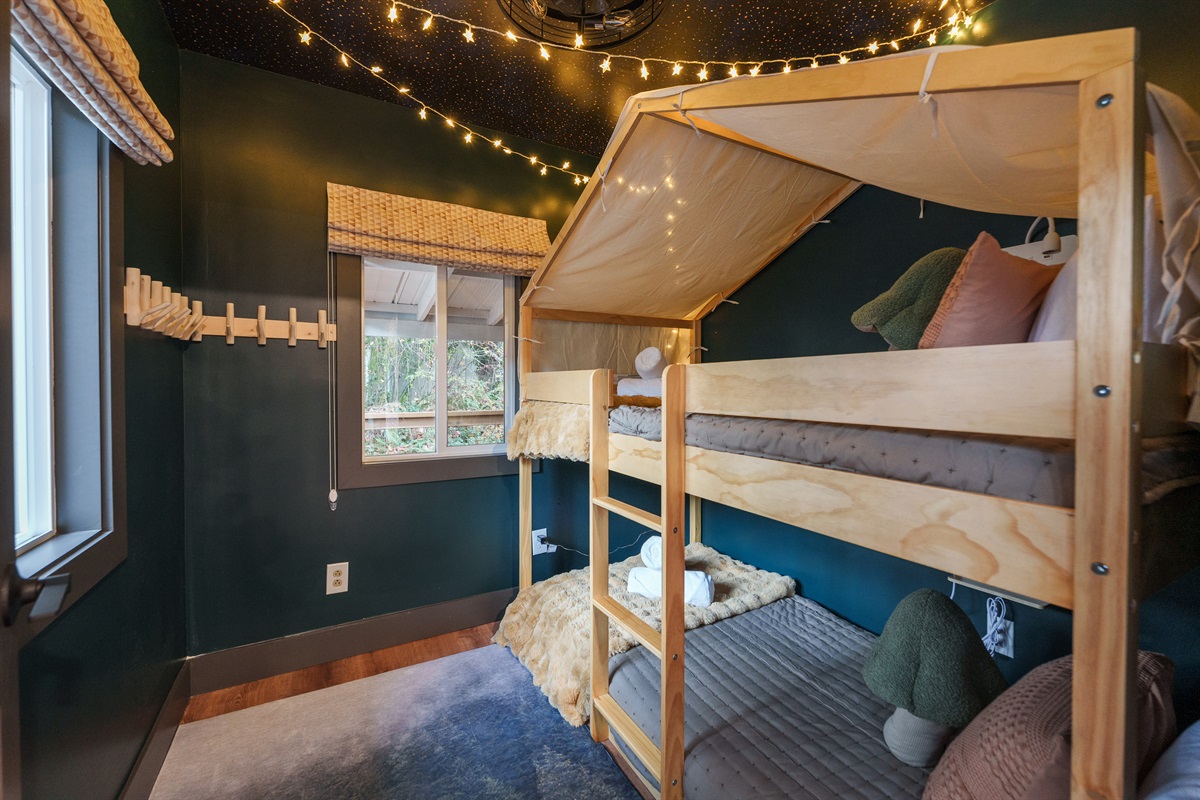 A magical campout bunk room kids adore, complete with twinkling lights, comfy bedding, and a cozy hideaway vibe perfect for nighttime adventures.