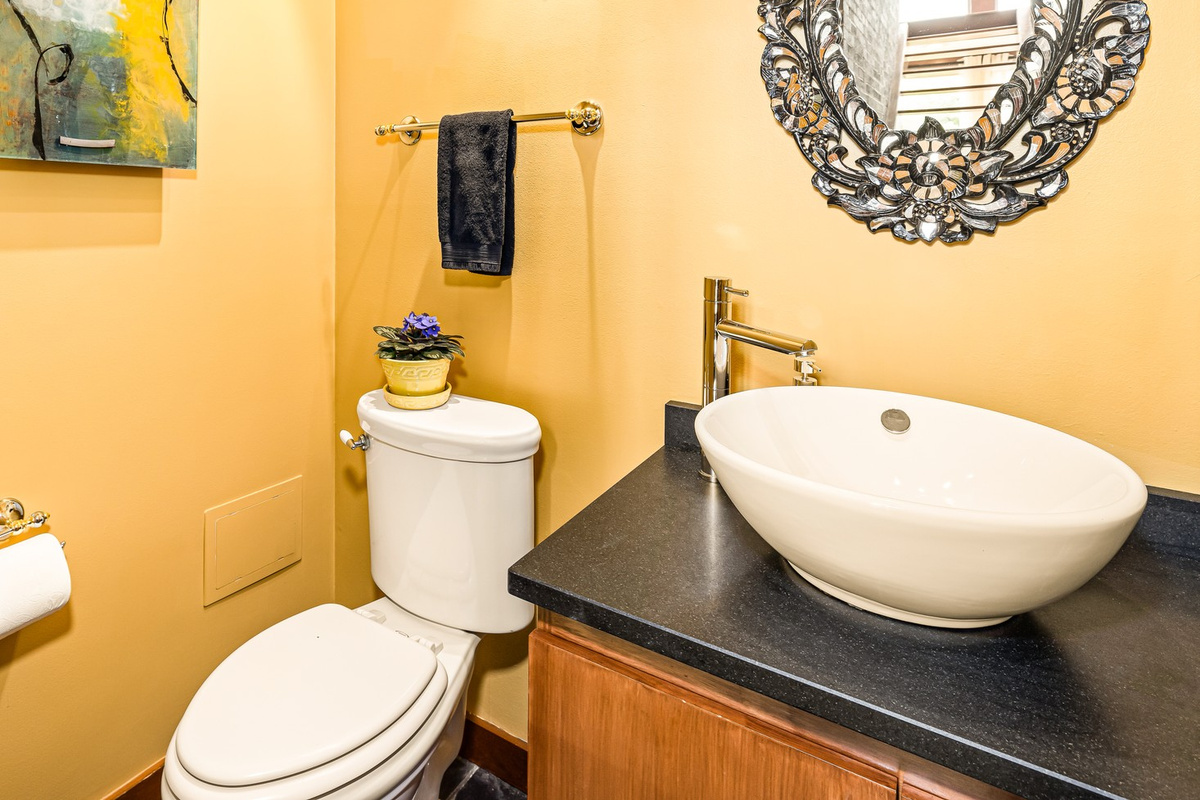 Main floor Powder Room is conveniently located off of the Great Room. The luxe stone counter, vessel sink, antique hand-cut glass mirror, and contemporary art add to Hilltop Oasis Abingdon's curated design experience.