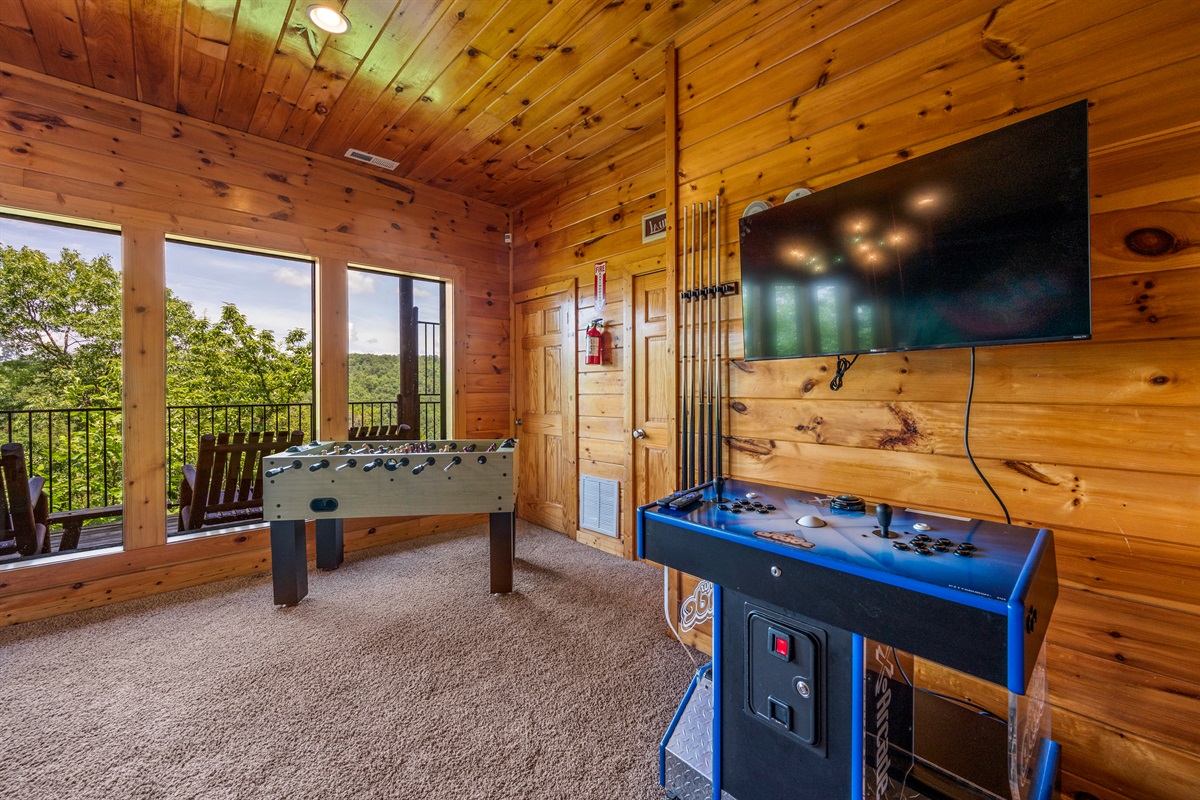 Game room with large windows offering a scenic mountain views and access to a balcony with rocking chairs