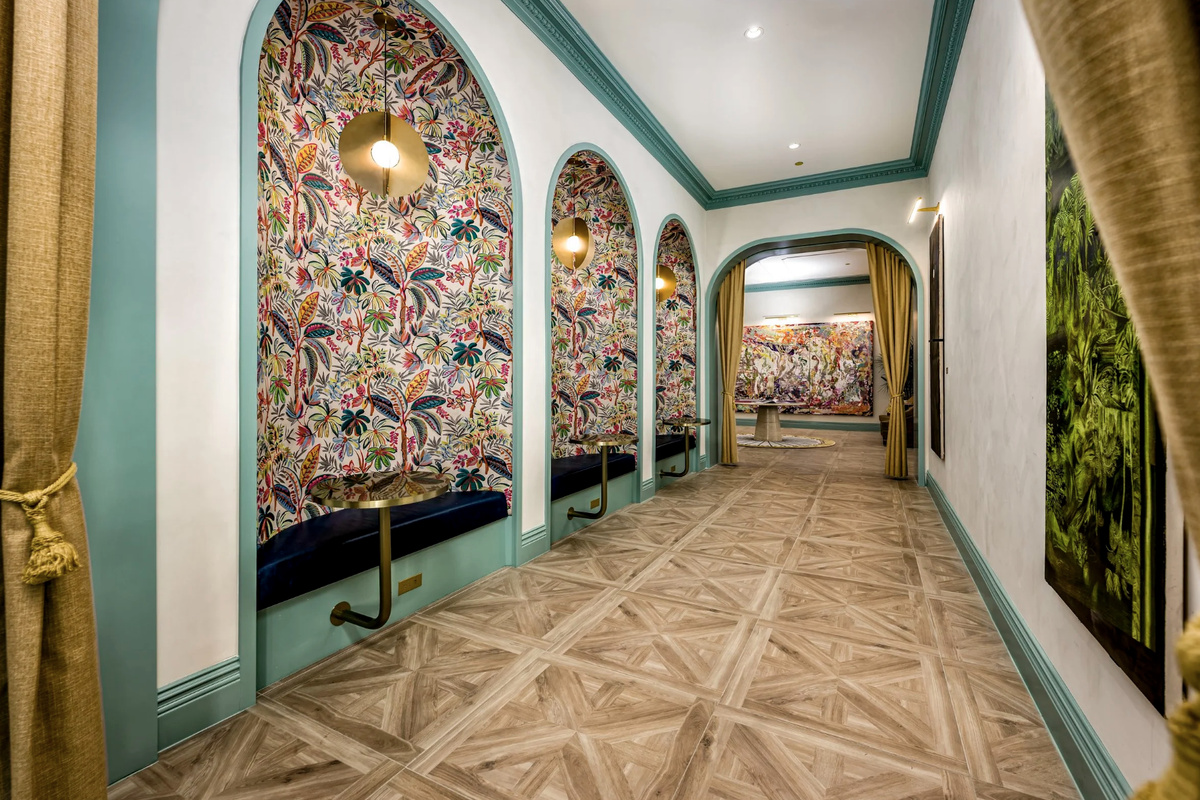 A gallery-inspired corridor in rich pattern and arched detailing leads through the building's curated interiors.