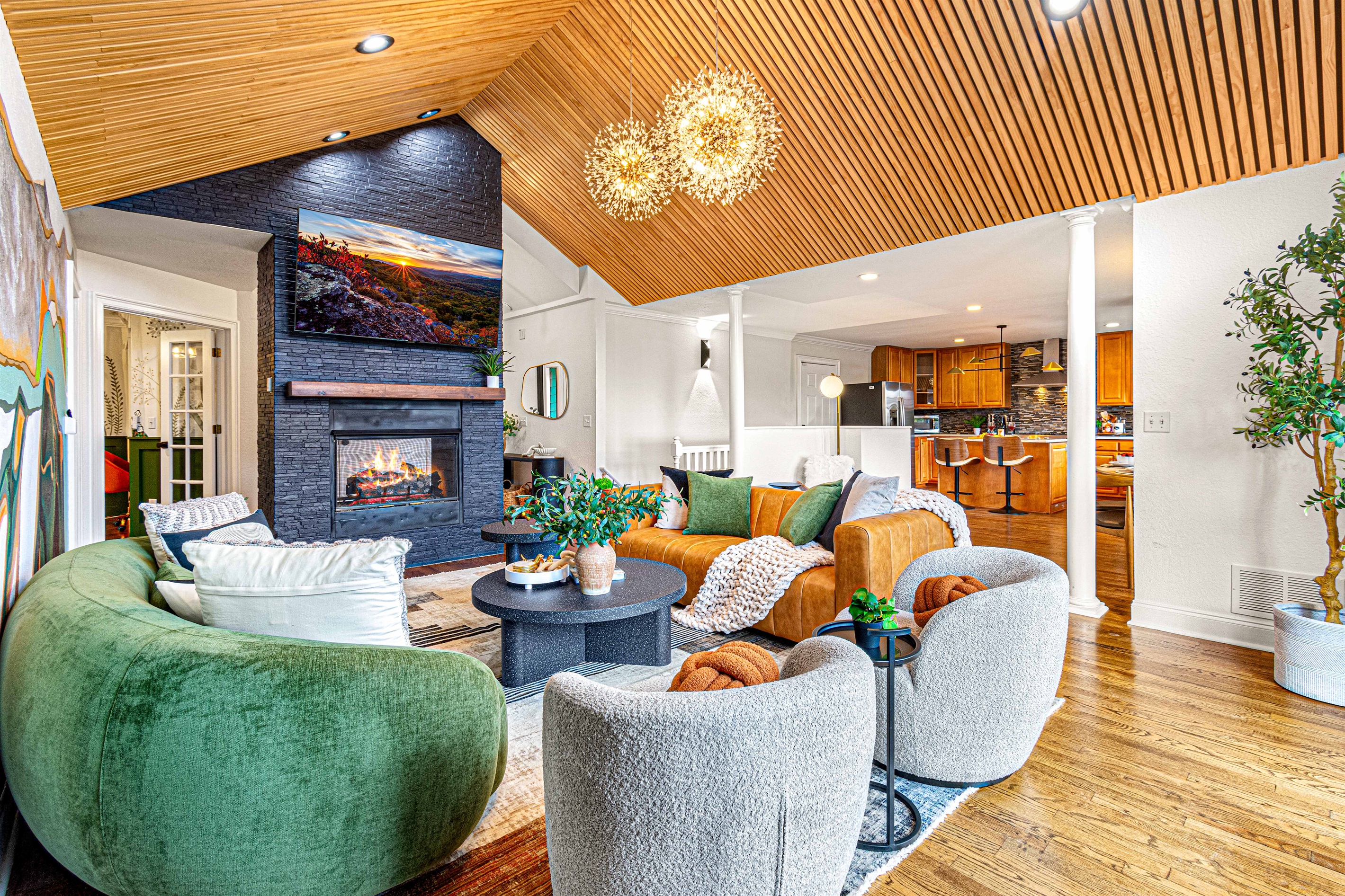 Gather in this stunning living room with a vaulted wood ceiling, cozy fireplace, and modern decor. A perfect spot to relax and enjoy the warmth and ambiance.
