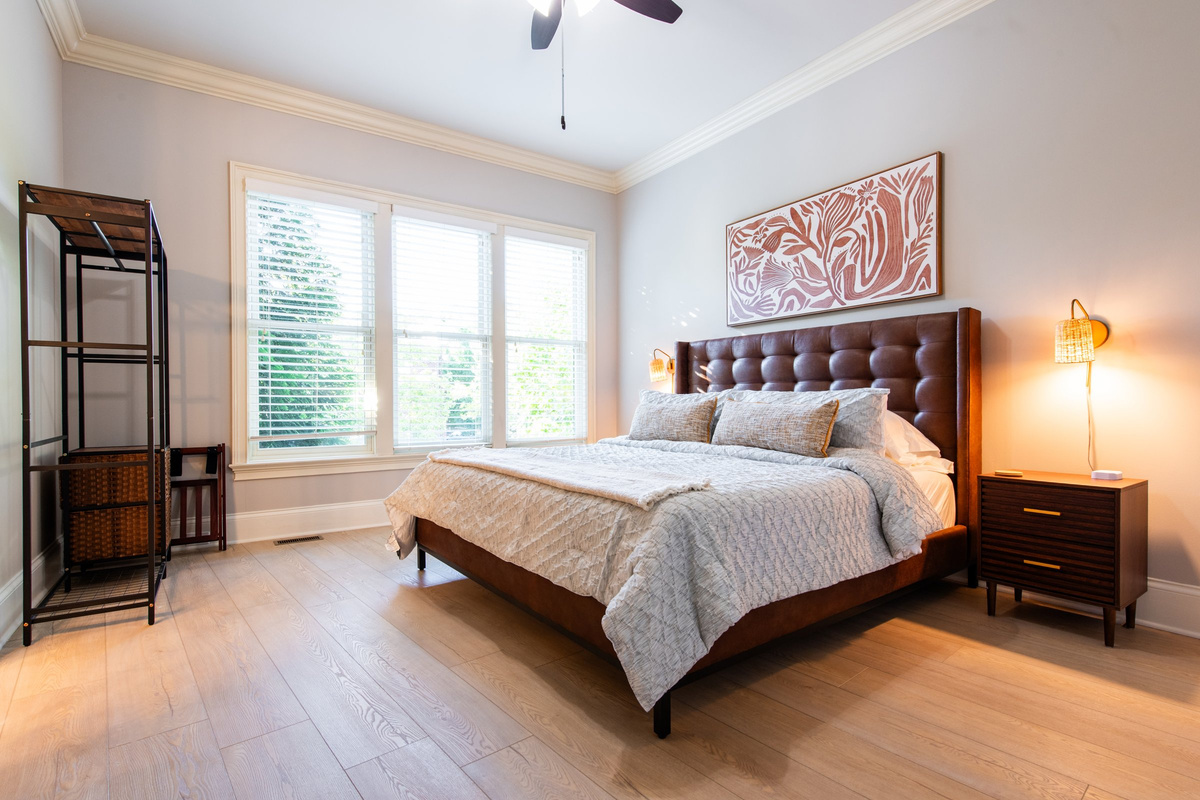 A second bedroom with a tufted leather headboard and private ensuite bath.