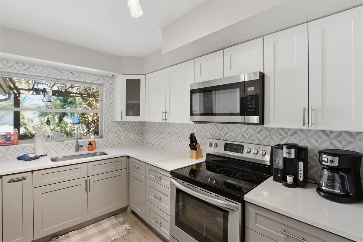 Fully renovated & stocked kitchen with quartz and stainless steel appliances.