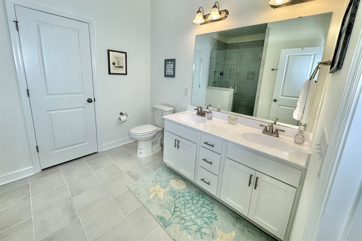 Master bathroom has a ceiling-to-floor tile shower with glass enclosure and 2 sinks.