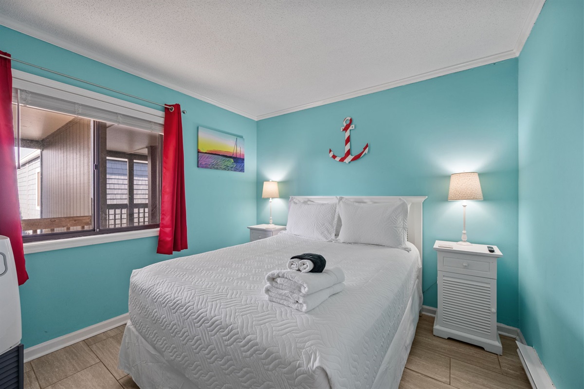 Cozy queen bedroom with bright coastal colors and soft linens for a restful night after a beach day