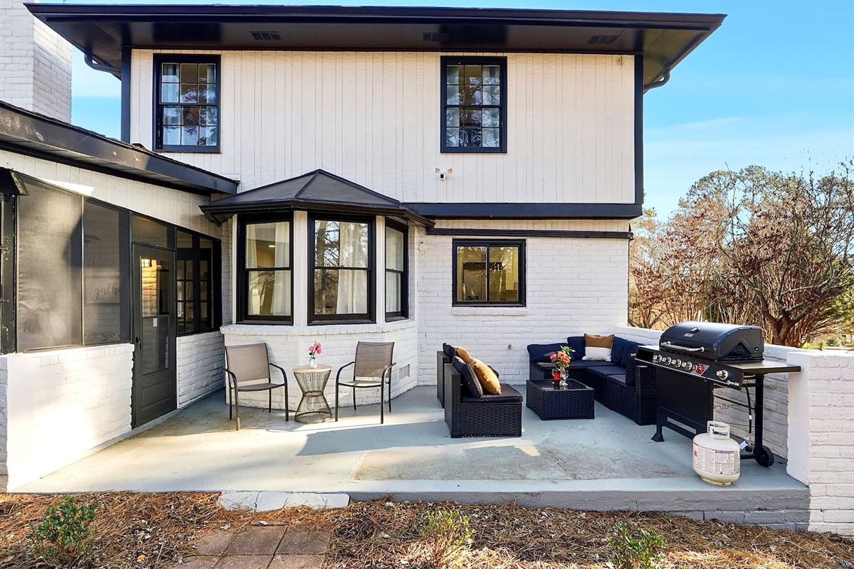 Inviting patio with black outdoor furniture, beige chairs, and a propane grill. A great space to relax, dine outside, or enjoy time with friends and family.