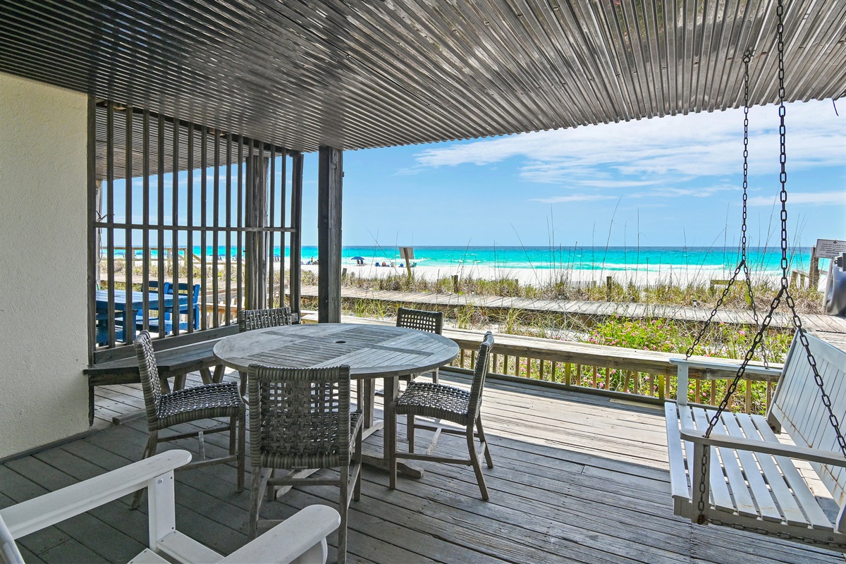 Covered patio on the first level with seating, beach gear storage, outdoor shower, and a porch swing - come and relax!