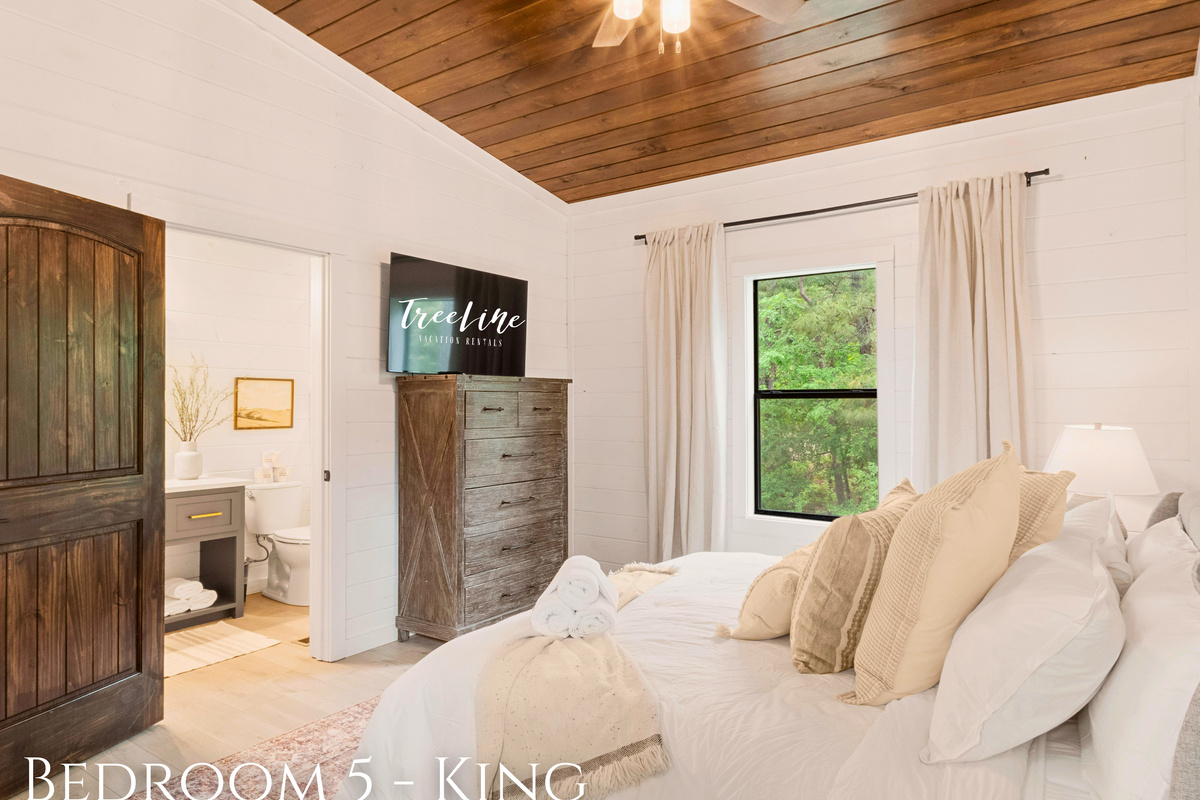 Cozy king bedroom with a plush bed, inviting decor, and tranquil nature views from the window.