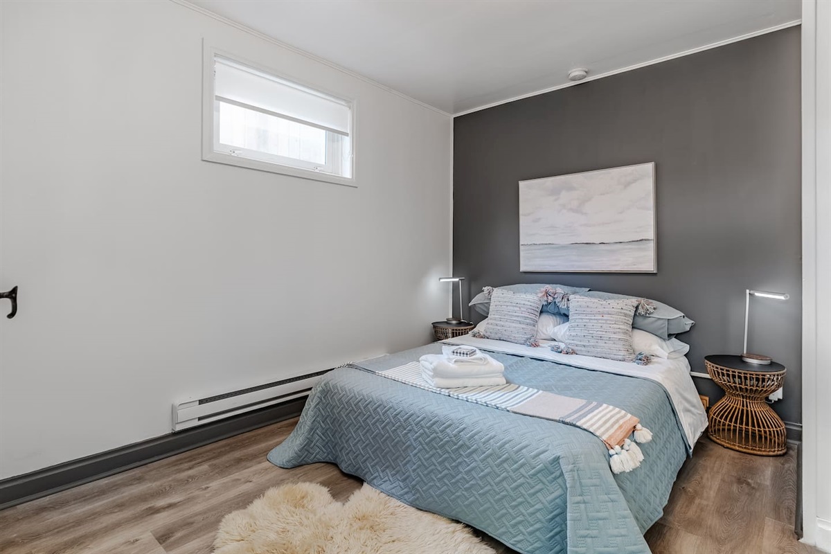 Comfortable basement bedroom with queen bed and soft lighting