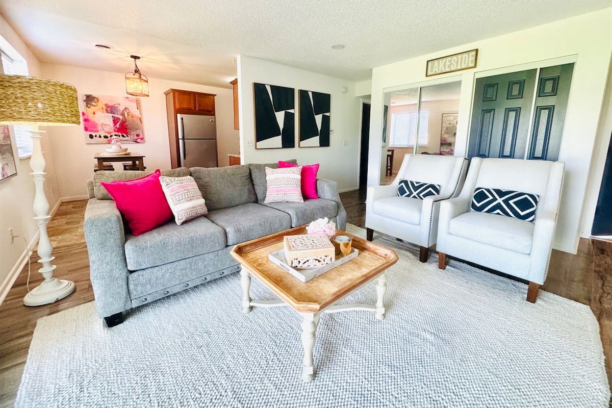 Bright and inviting living space with colorful floral decor, comfortable seating, and a playful area rug. Sliding glass doors open to scenic views, filling the room with natural light—perfect for morning coffee or evening unwinding.