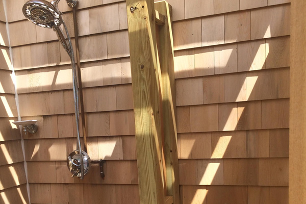 outside shower with rain shower head and dressing area with bench.