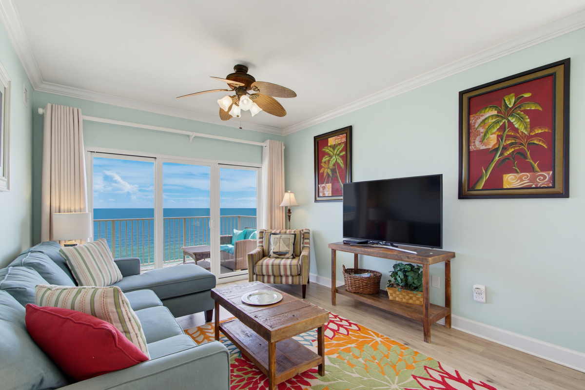 Living-area seating beside floor-to-ceiling Gulf views and a TV.